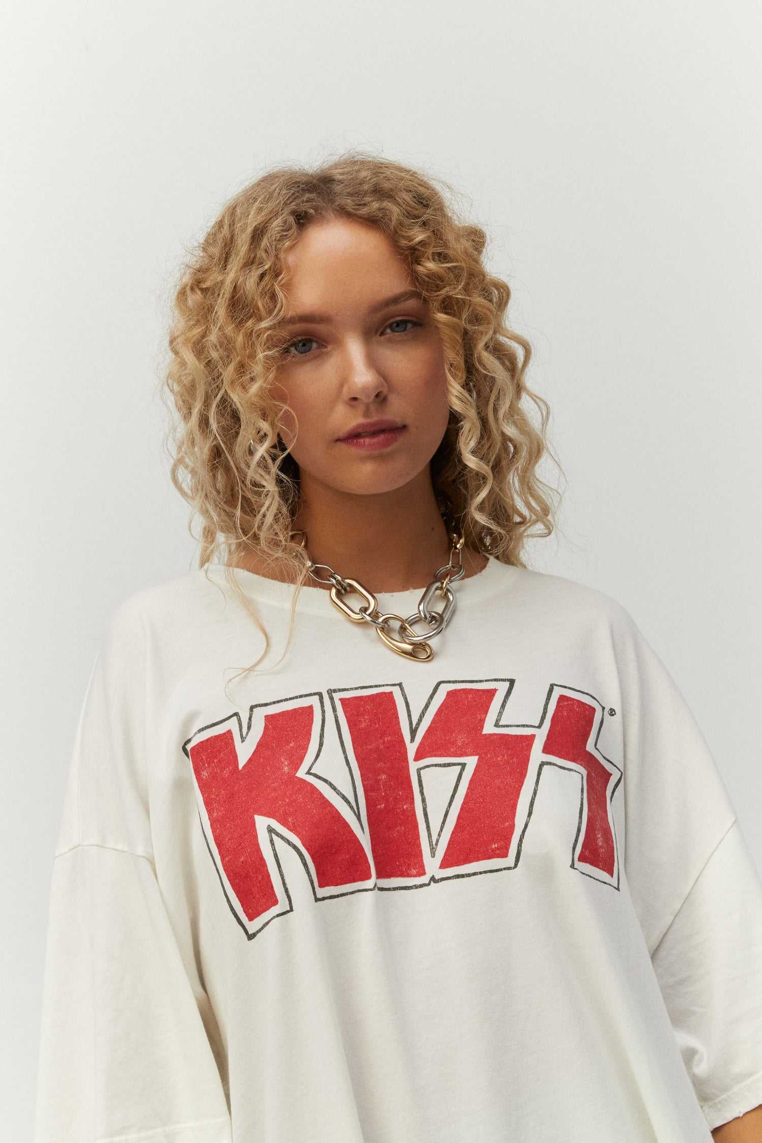 Blonde curly-haired model featuring a white tee designed with Kiss’ logo in iconic red glitter