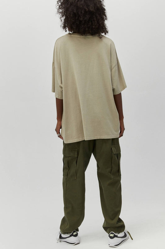 Dark curly-haired model featuring a solid desert green oversized tee