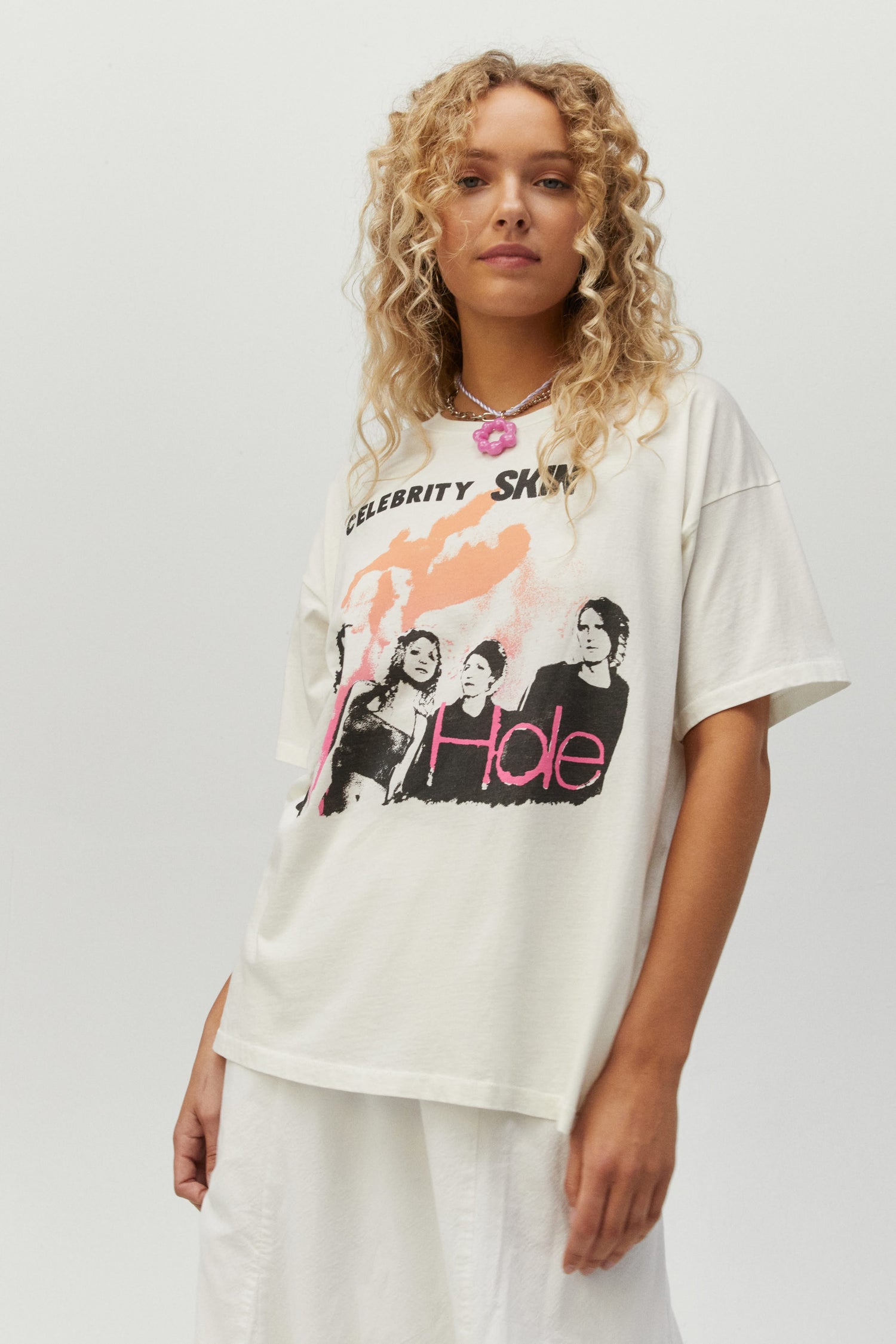 Blonde curly hair model featuring A rendition of the album cover on this 90s inspired merch tee stamped with portraits of the group on the back. 