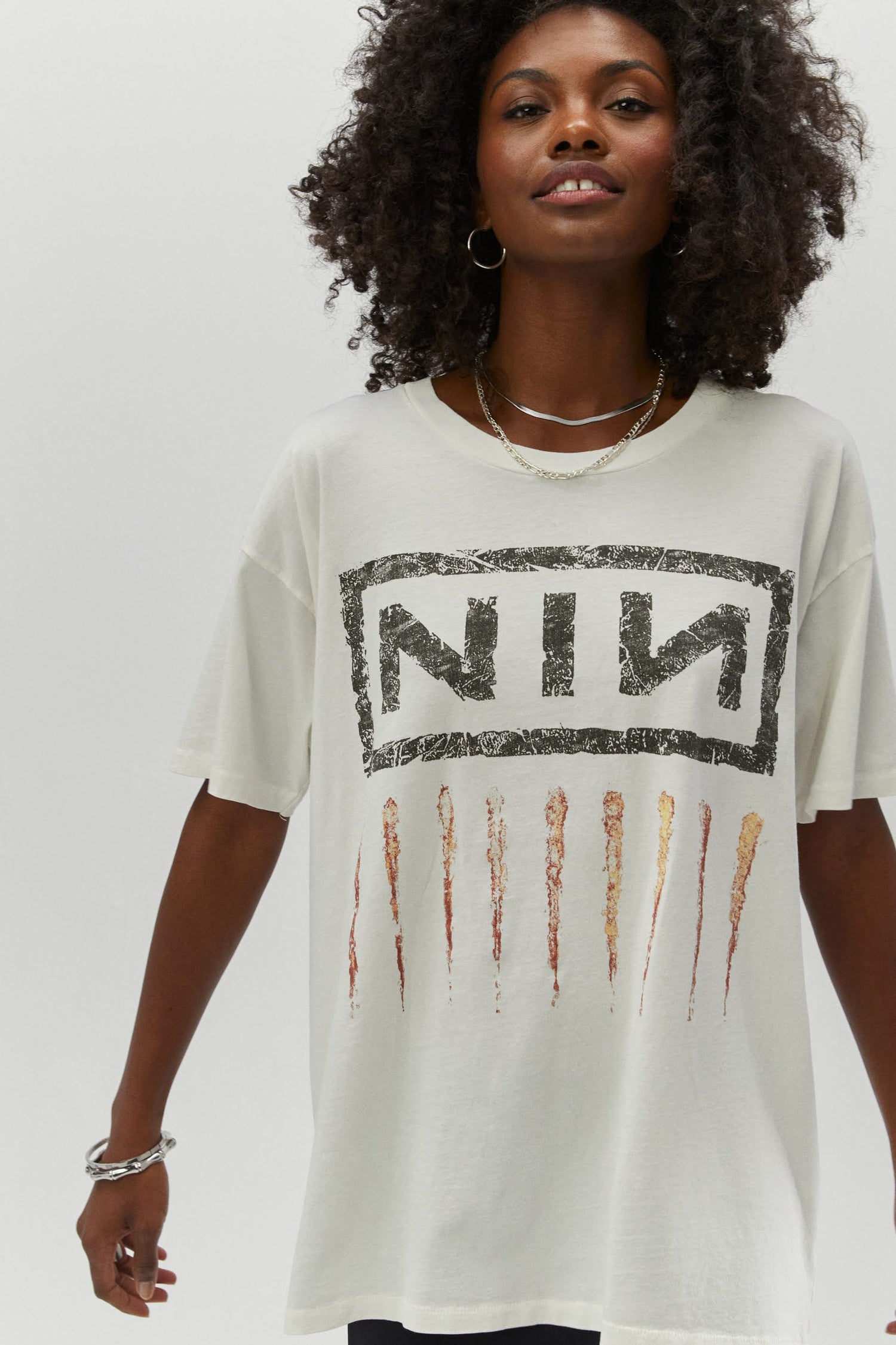 A dark curly-haired model featuring a white tee designed with their logo lands on this roomy merch tee with a tribute to one of the most important albums of the 90s,