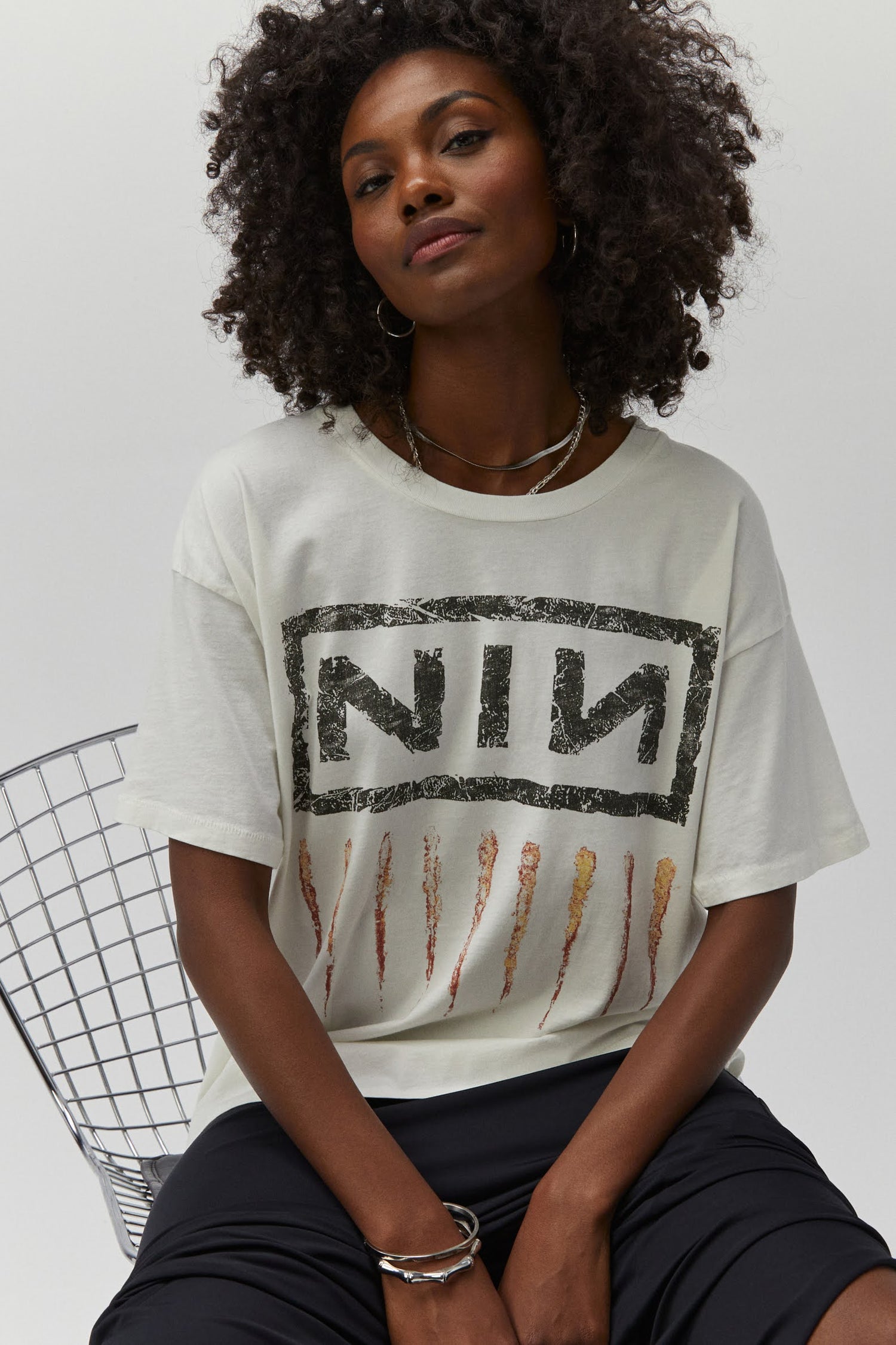 A dark curly-haired model featuring a white tee designed with their logo lands on this roomy merch tee with a tribute to one of the most important albums of the 90s,